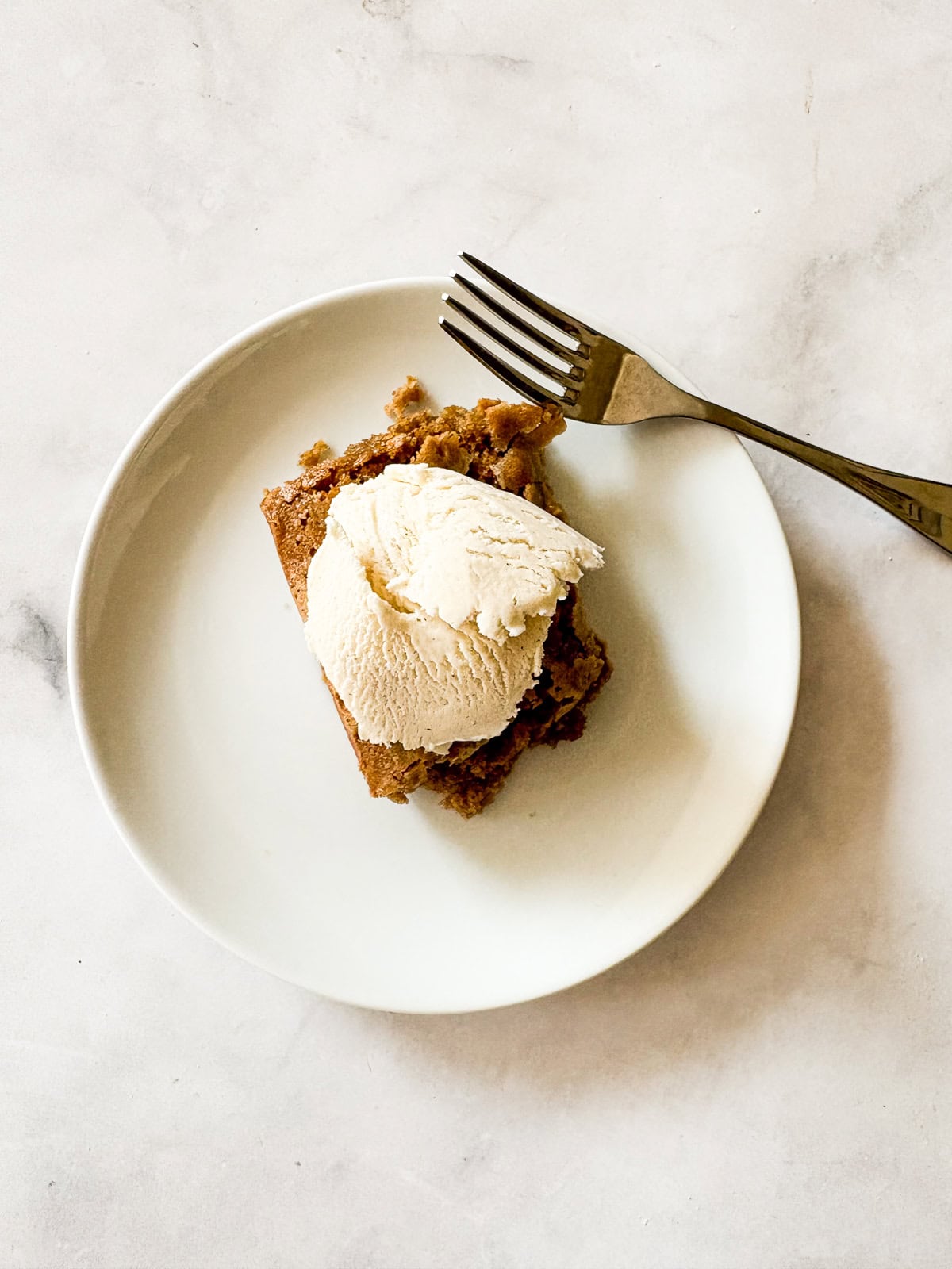 A gluten free brown butter pumpkin square on a plate with ice cream.