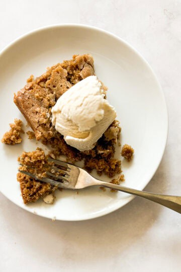 A gluten free pumpkin square on a plate with ice cream and a fork.