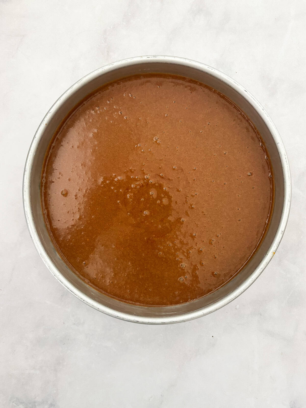 This gluten free chocolate cake with caramel frosting is rich, tender, and deeply chocolatey, perfect for birthdays or any celebration. Chocolate cake batter in a cake pan.