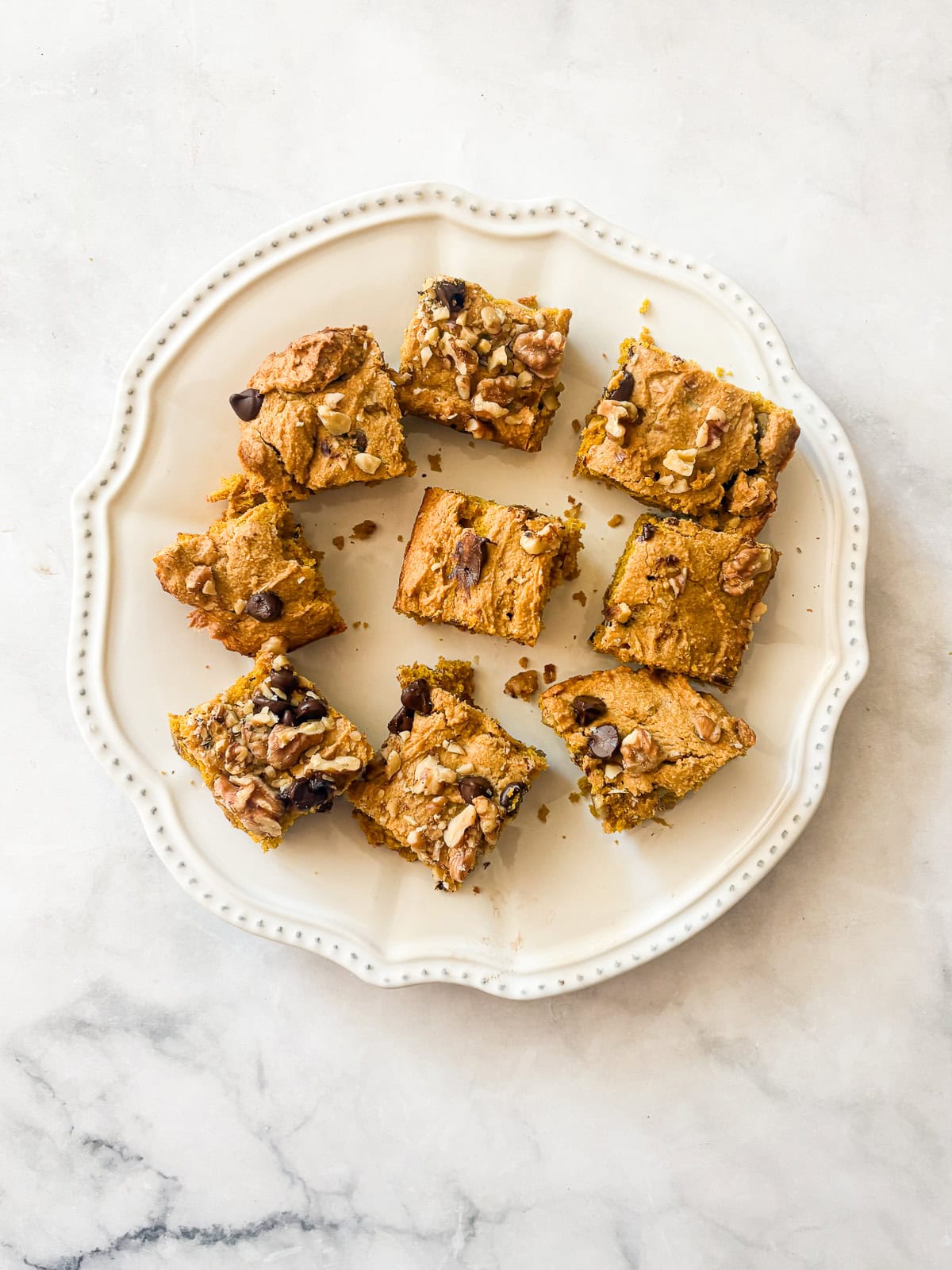 Studded with chopped walnuts and scattered with semisweet chocolate chips, gluten-free pumpkin blondies are thick and chewy. Made in 1 bowl! A plate of gluten free pumpkin blondies.