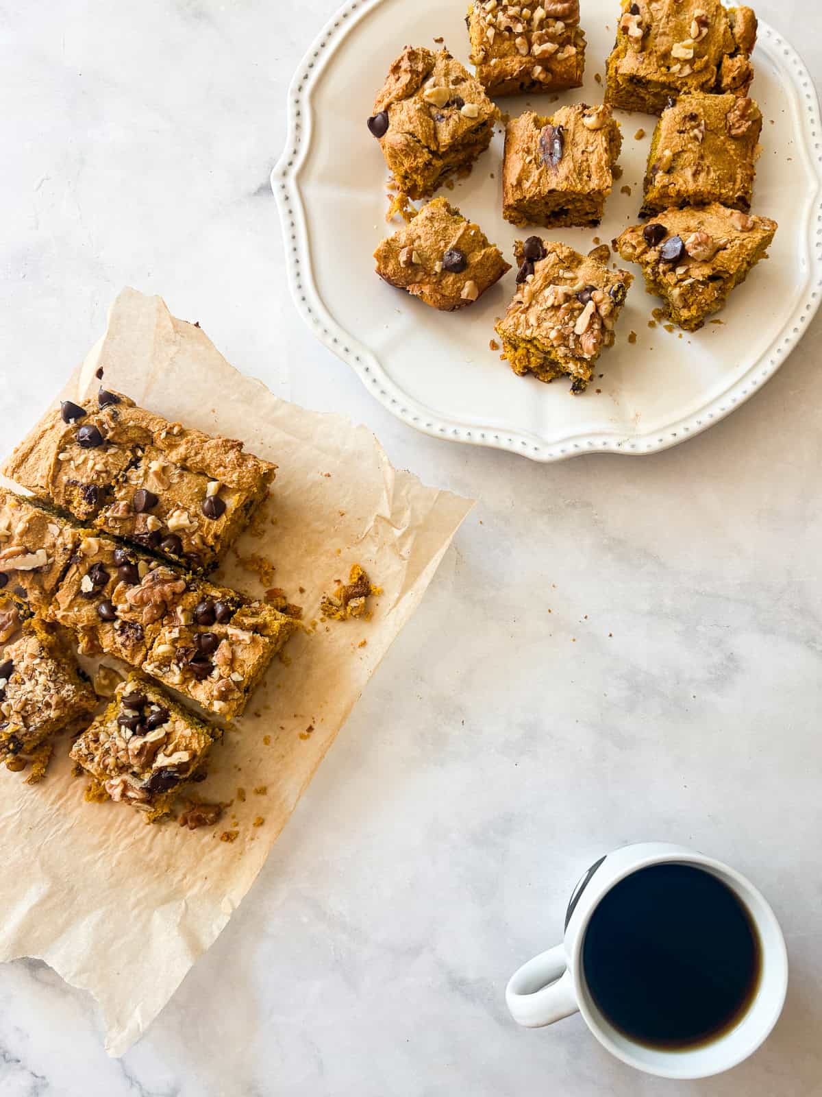 Studded with chopped walnuts and scattered with semisweet chocolate chips, gluten-free pumpkin blondies are thick and chewy. Made in 1 bowl! Gluten free pumpkin blondies and a cup of coffee.