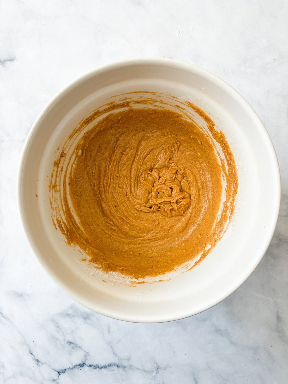 Studded with chopped walnuts and scattered with semisweet chocolate chips, gluten-free pumpkin blondies are thick and chewy. Made in 1 bowl! The combined batter for gluten free pumpkin blondies in a large bowl.