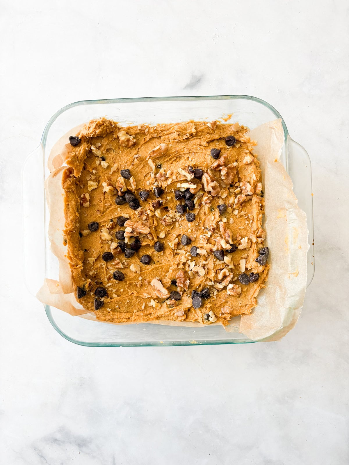 Studded with chopped walnuts and scattered with semisweet chocolate chips, gluten-free pumpkin blondies are thick and chewy. Made in 1 bowl! Pumpkin blondie batter is placed in a pan and topped with chocolate and nuts.