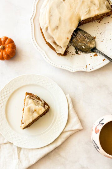 Pumpkin olive oil cake with a white napkin next to a cup of coffee.
