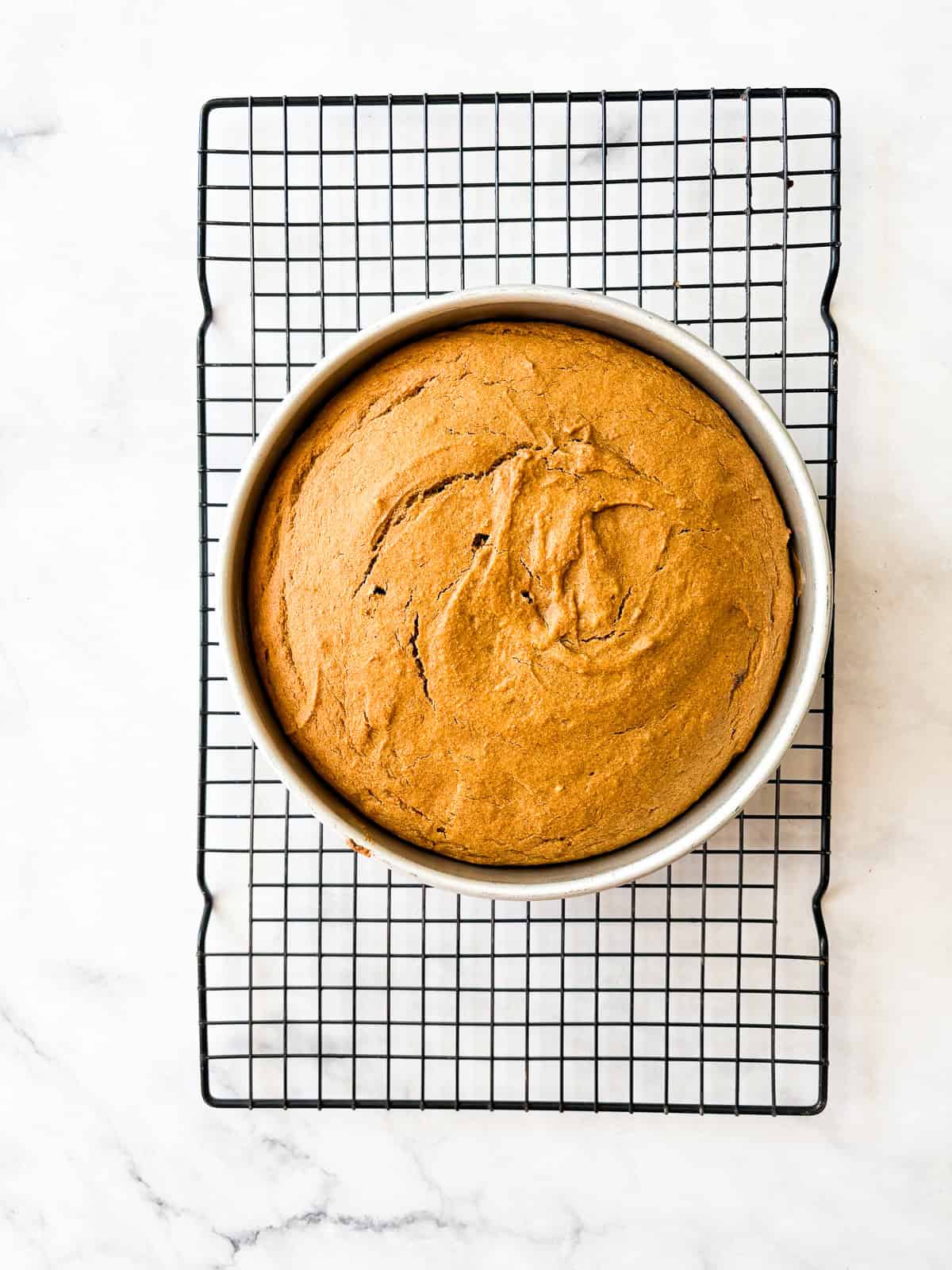 A thick maple glaze tops a soft gluten free pumpkin olive oil cake that's dairy-free, made in one bowl, and utterly delicious! A gluten free olive oil pumpkin cake cools in a cake pan.