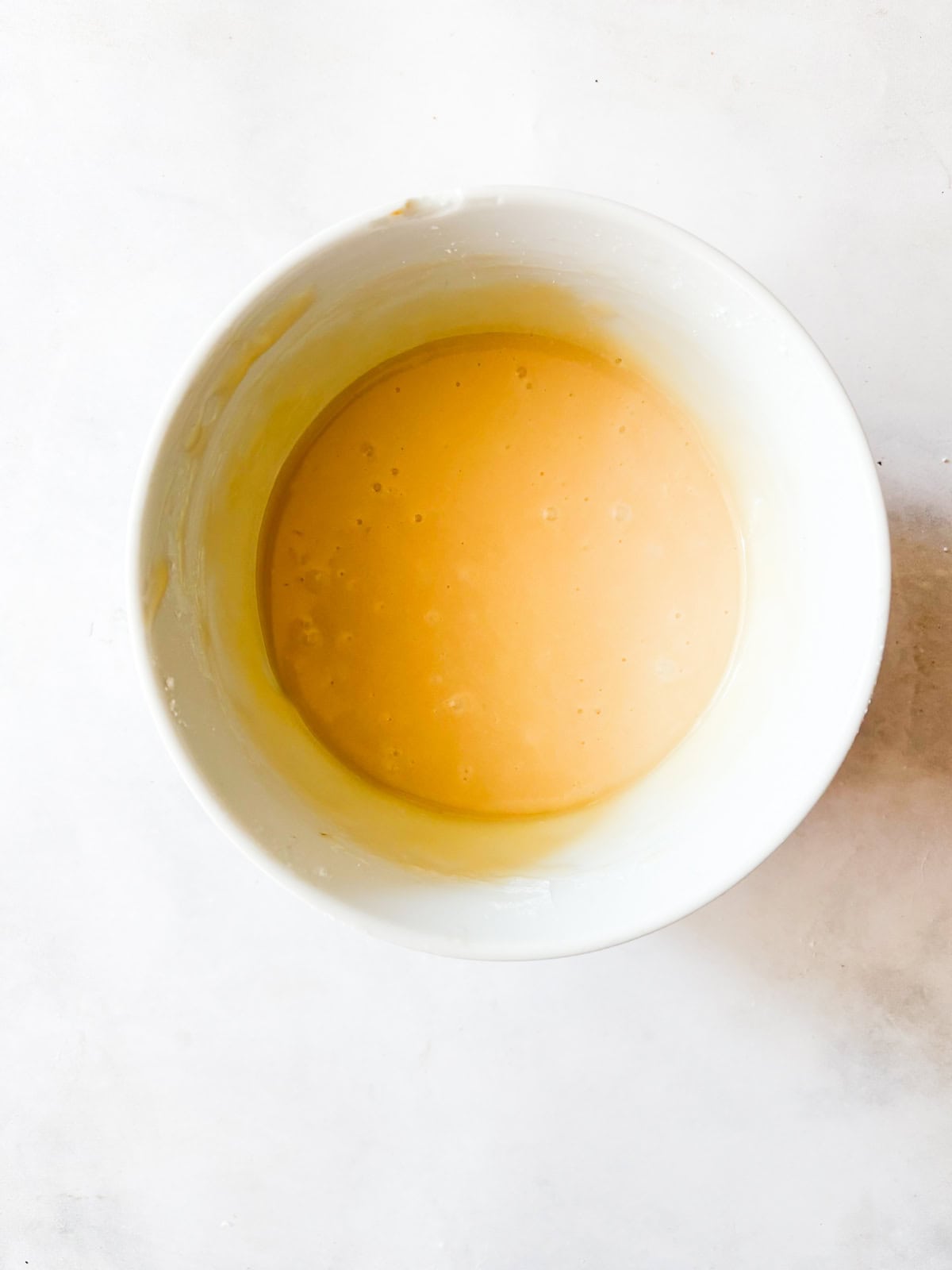 A thick maple glaze tops a soft gluten free pumpkin olive oil cake that's dairy-free, made in one bowl, and utterly delicious! Maple glaze mixed in a bowl.