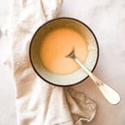 A bowl of maple glaze on a white napkin with a spoon.