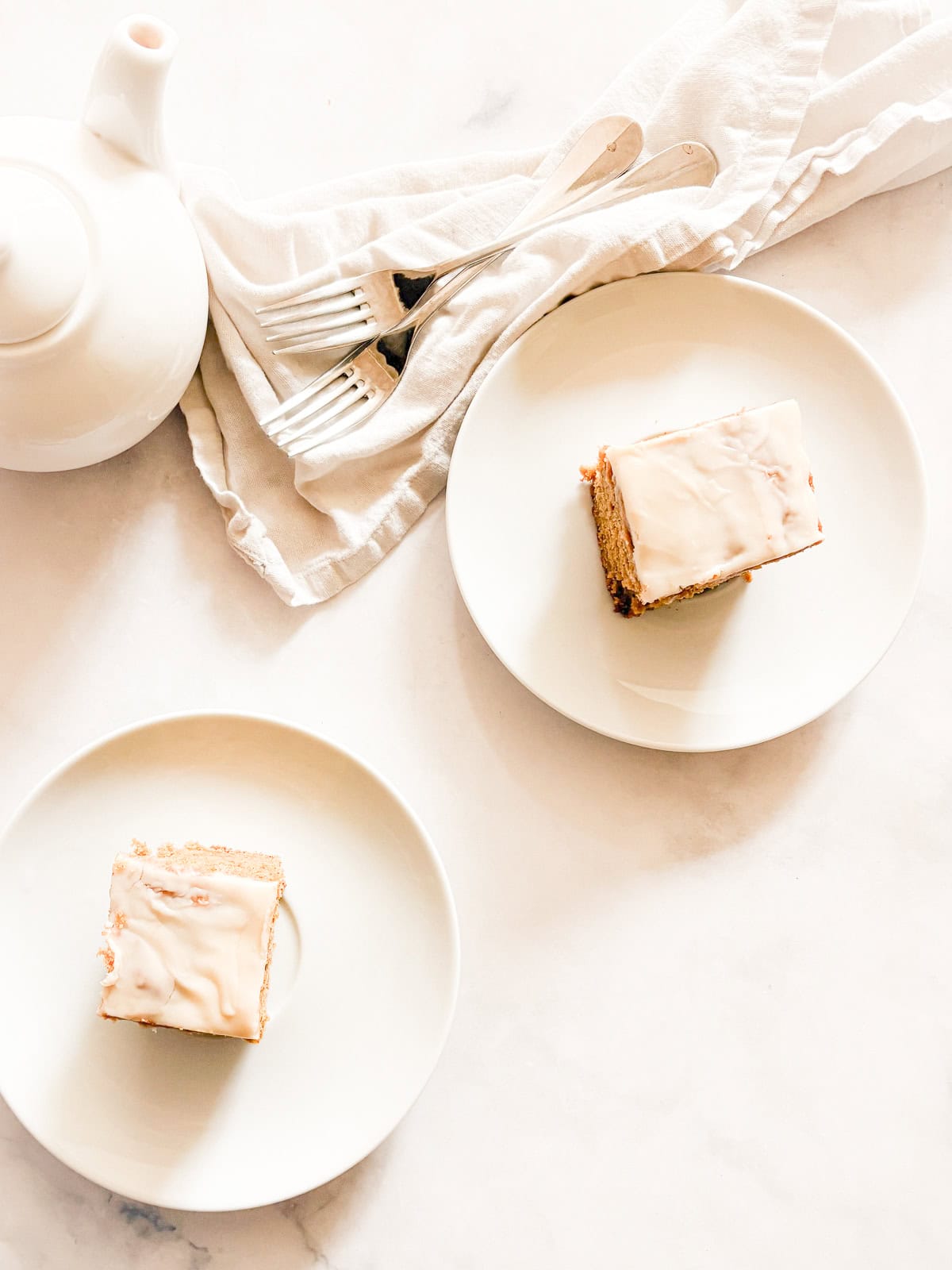 This smooth and luxurious maple glaze recipe needs just three simple ingredients to make and is wonderful on scones, pumpkin bread, and more. Maple glaze tops pieces of pumpkin cake.
