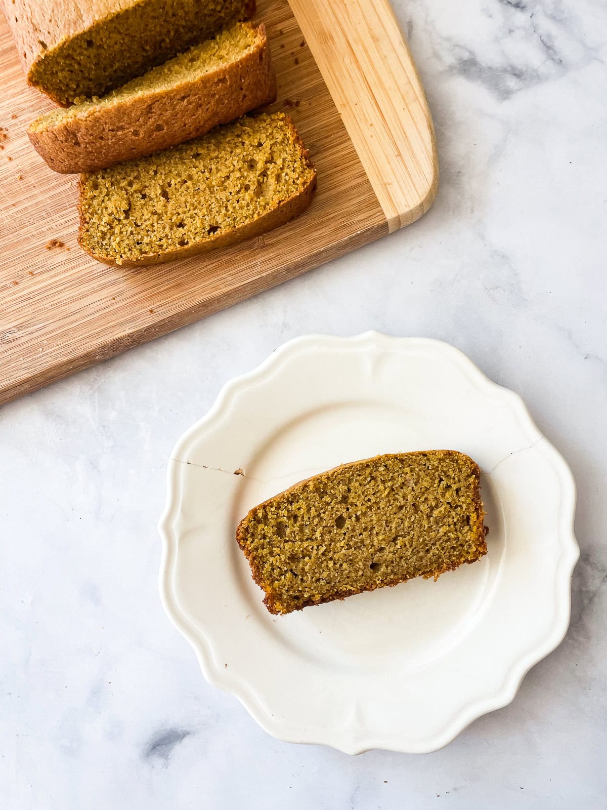 Slices of oat flour pumpkin bread on a cutting board and a plate.