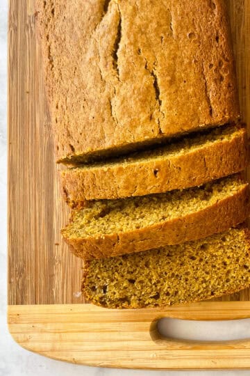 A sliced loaf of oat flour pumpkin bread on a cutting board.