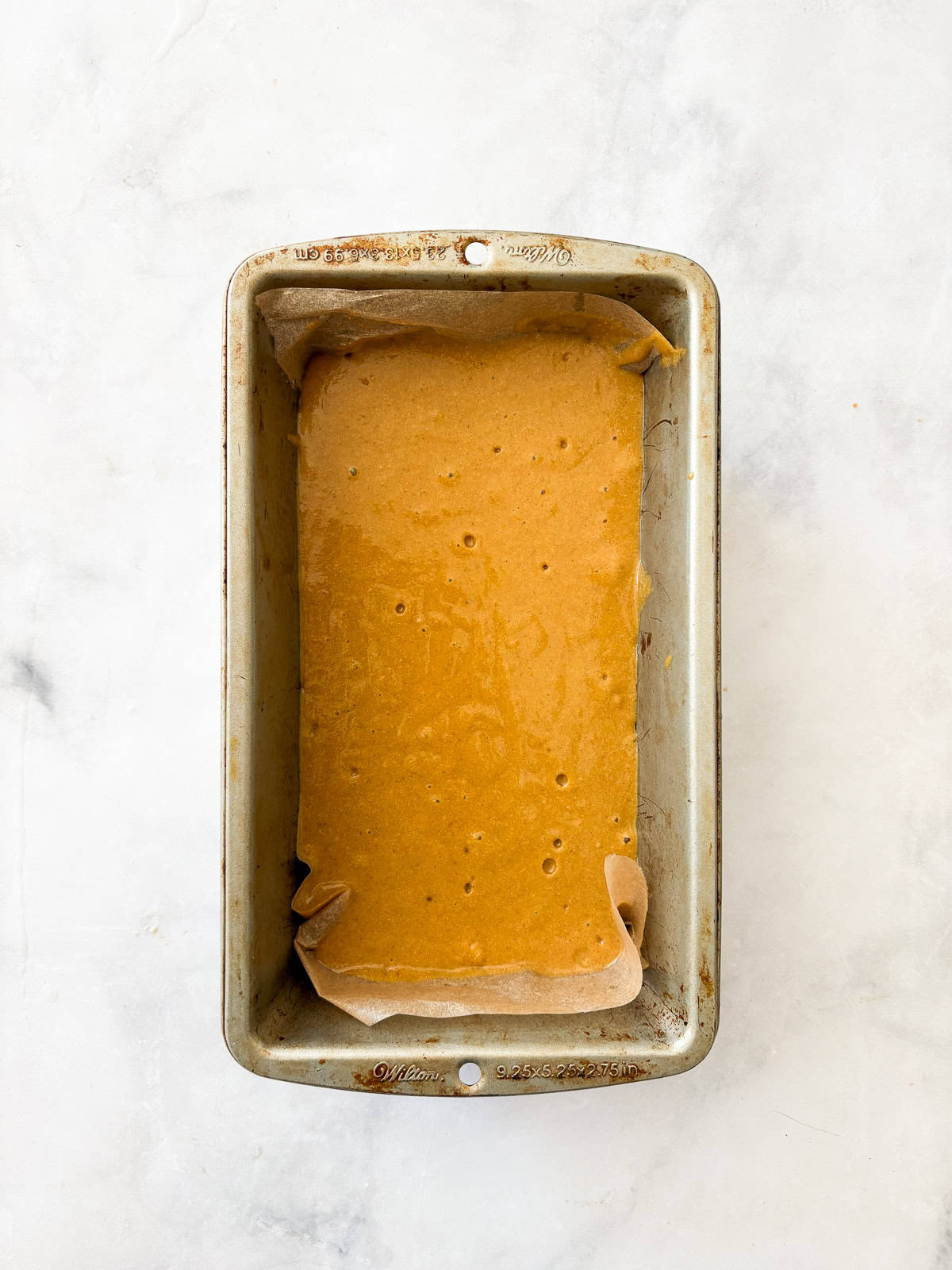 A loaf pan full of oat flour pumpkin bread batter.