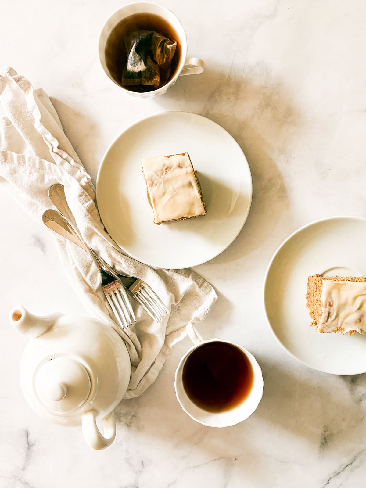 A soft, fluffy, and warmly spiced oat flour pumpkin cake that's topped with a slick of sweet maple glaze. Naturally gluten-free! Two cups of tea and two slices of oat flour pumpkin cake.
