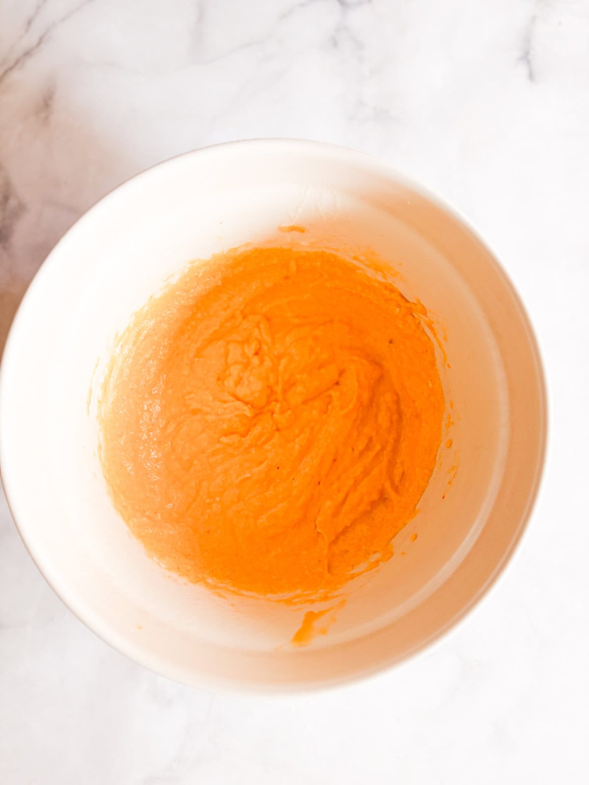 A soft, fluffy, and warmly spiced oat flour pumpkin cake that's topped with a slick of sweet maple glaze. Naturally gluten-free! Wet mix for oat flour pumpkin cake in a bowl.