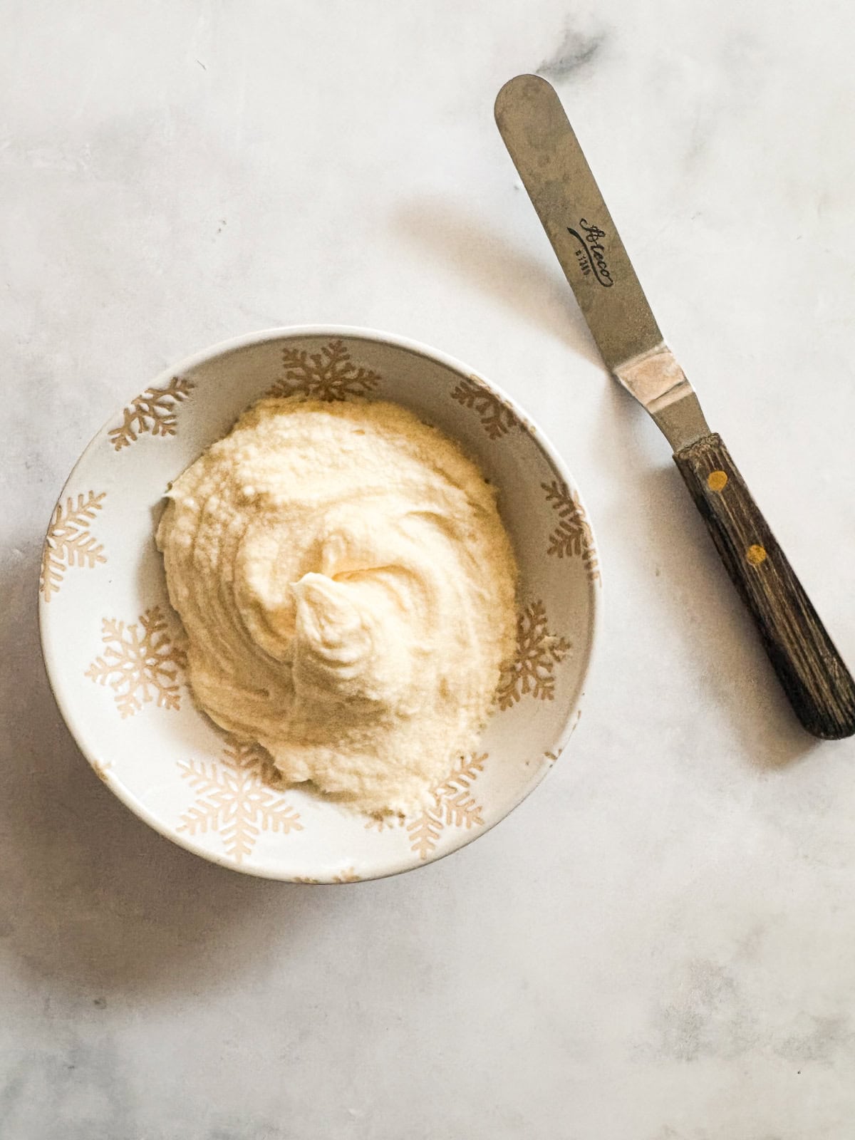Salted caramel frosting is sweet-salty, creamy, and just fluffy enough. Perfect on everything, from cakes to cupcakes to brownies. An offset spatula next to a bowl of salted caramel buttercream.