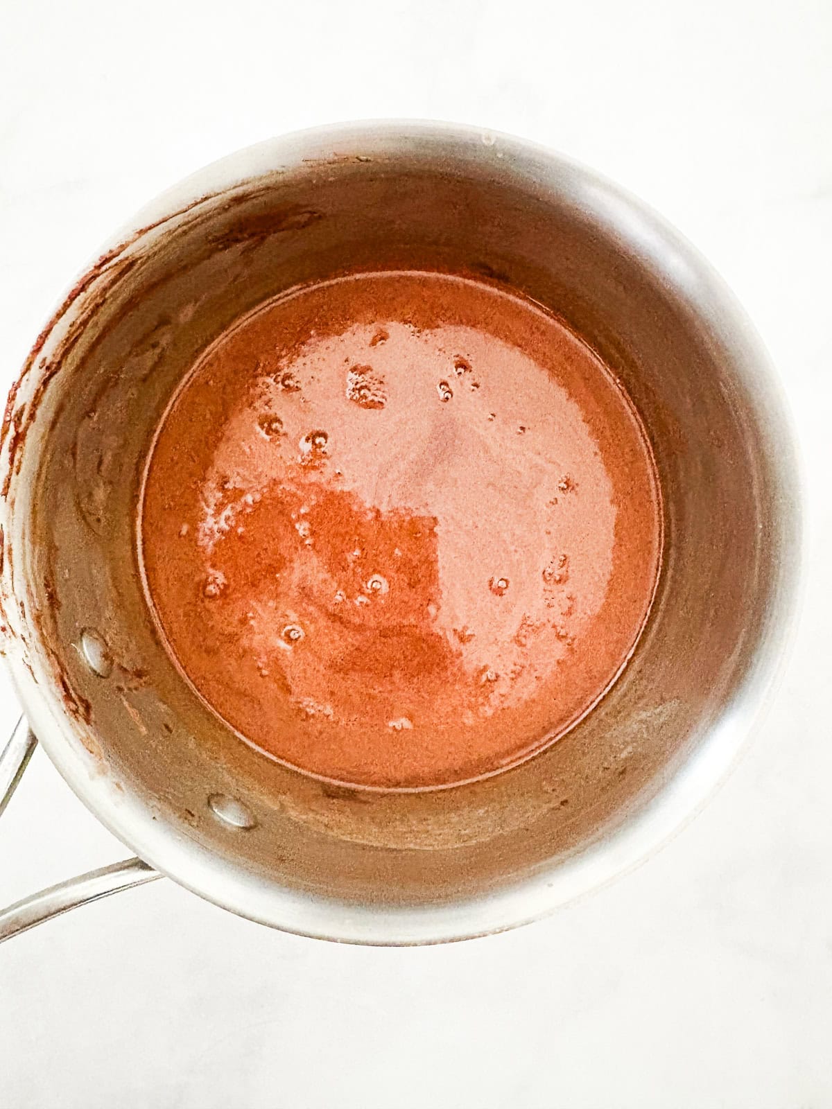 This gluten-free chocolate dump cake hits all the notes you want in a gluten-free cake - fudgy crumb, dense chocolate flavor, and creamy icing. A pot holds melted chocolate mixed with butter and sugar.