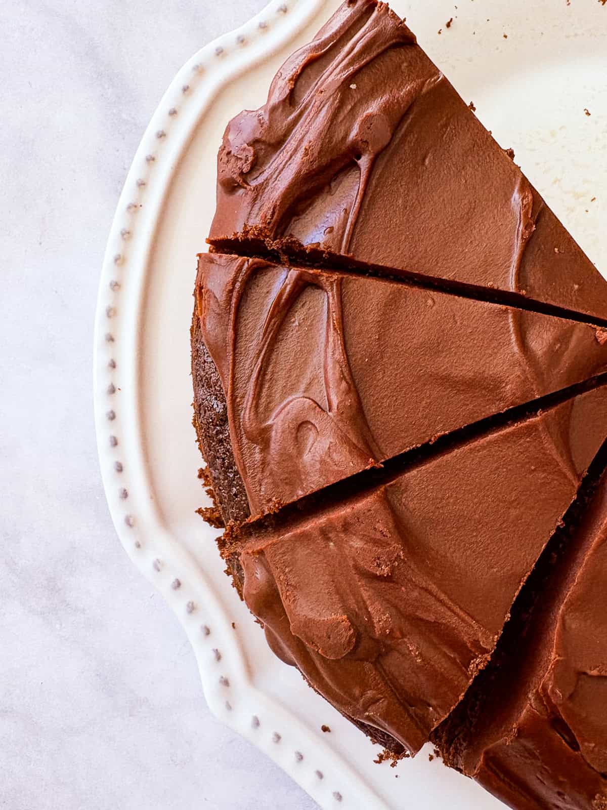 Slices of gluten free dark chocolate cake are cut from the cake.