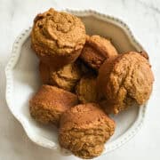 A white bowl of gluten free maple pumpkin muffins.