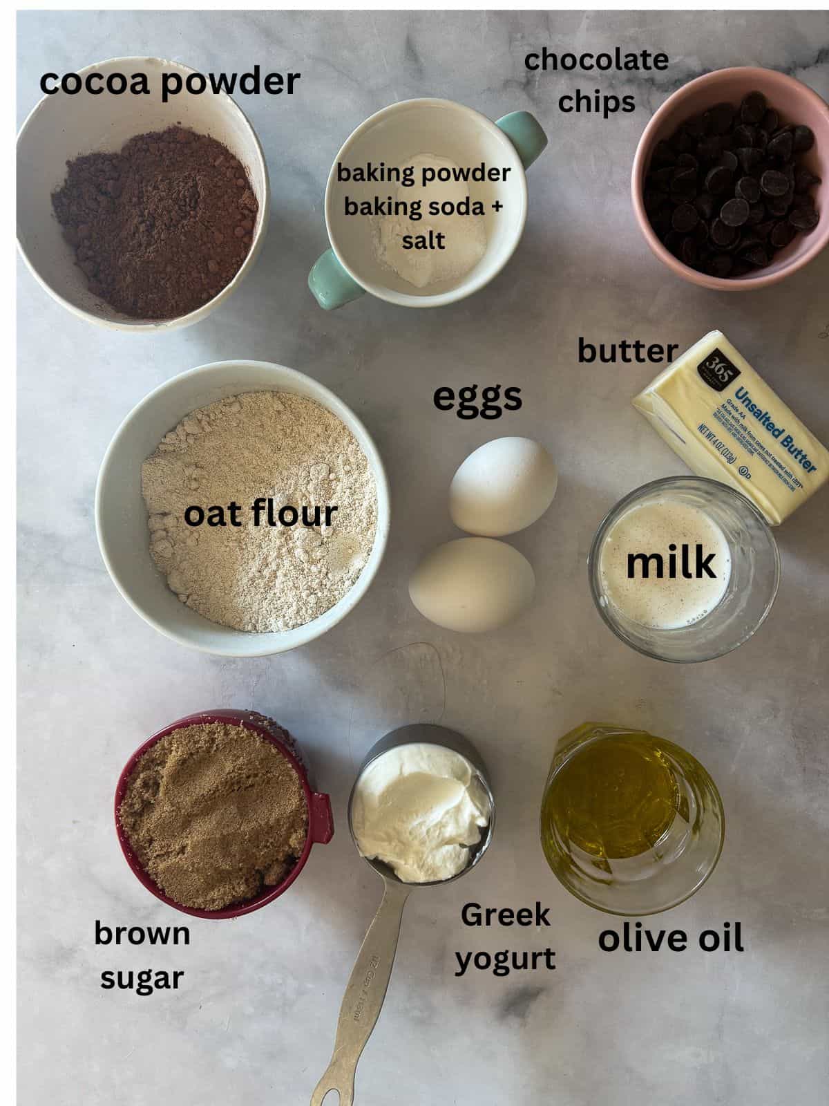 A tender, deeply dark gluten free chocolate olive oil cake capped with a layer of homemade chocolate icing. Ingredients for gluten free chocolate olive oil cake are text-labeled.