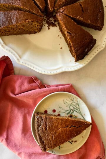 A slice of gingerbread cake on a plate with more slices nearby.
