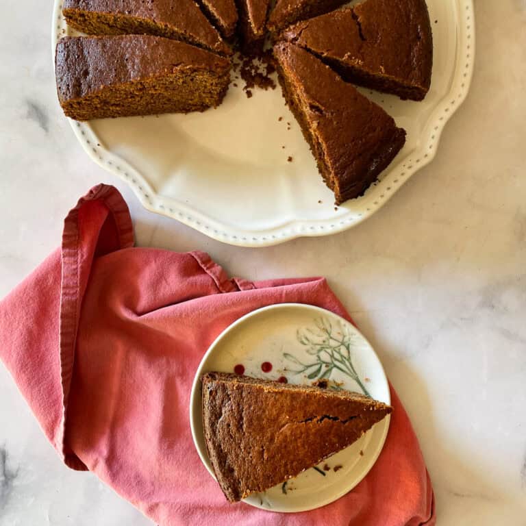 A slice of gingerbread cake on a plate with more slices nearby.