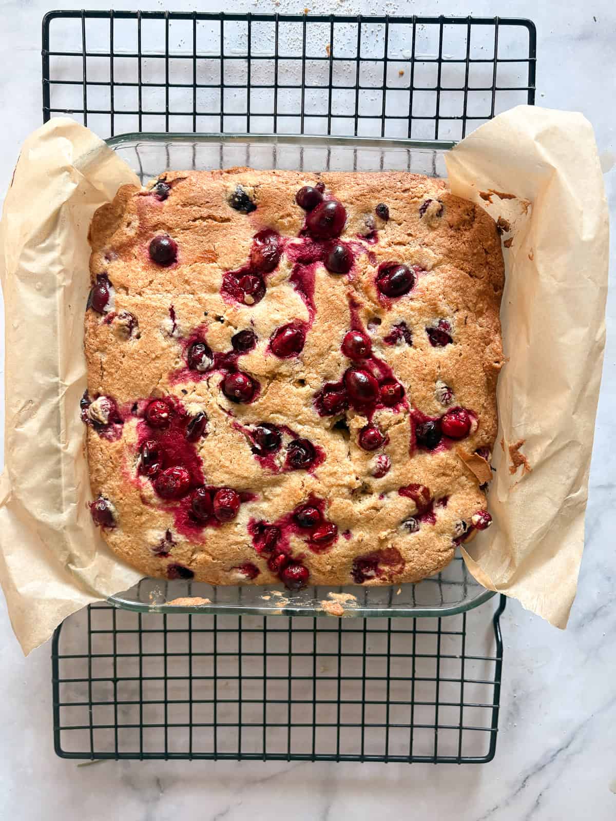 This beautifully festive gluten free cranberry cake is packed with juicy, tart berries that are balanced by a sweet, buttery cake. A gluten free cranberry cake cools in the pan.