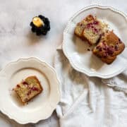 A candle burns next to slices of gluten free cranberry lemon loaf.
