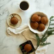 Gluten free gingerbread muffins on plates next to a bowl of muffins.