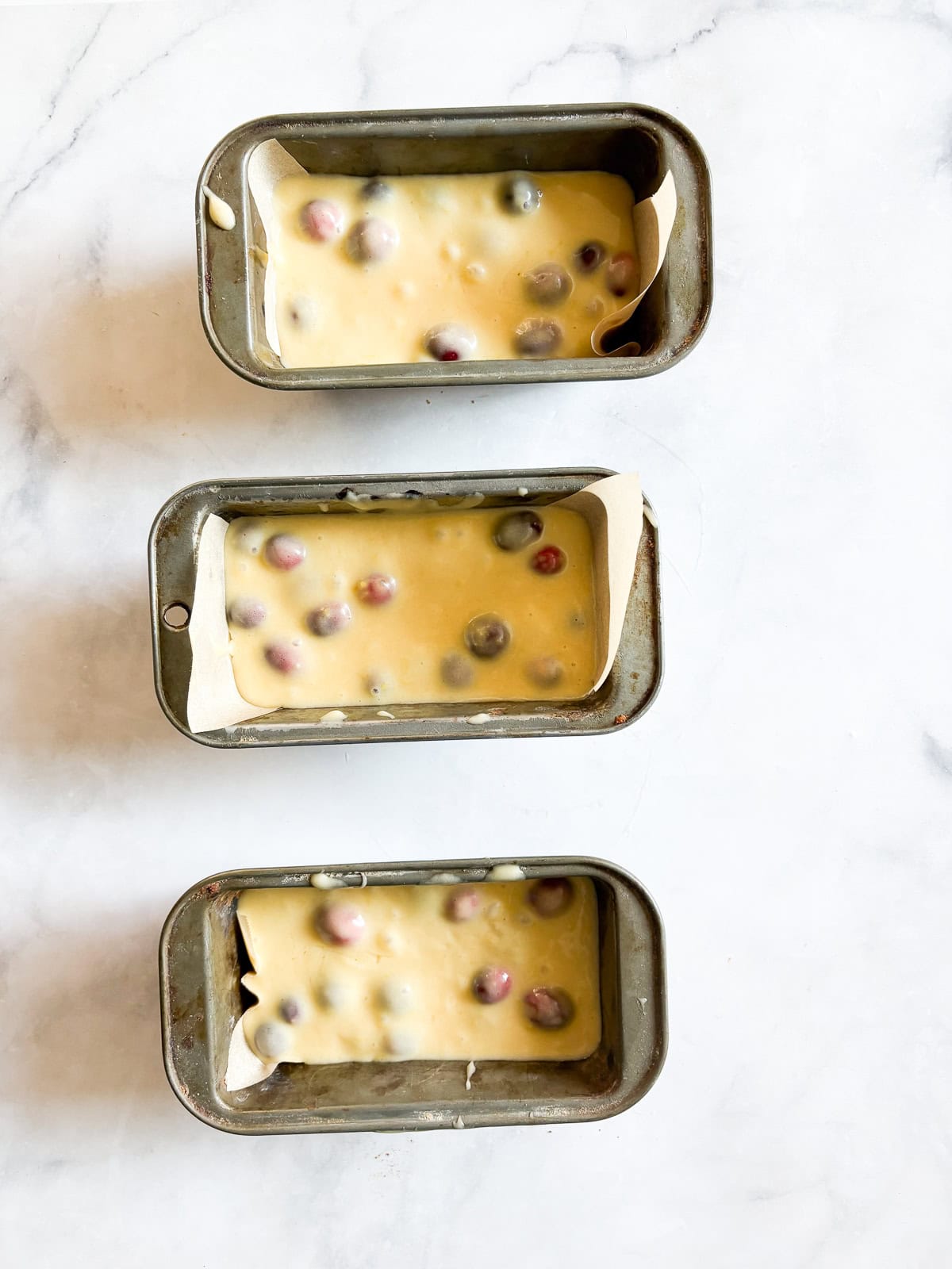 Perfect for holiday baking, this gorgeous gluten free cranberry lemon bread is studded with tart, juicy pops of cranberries. Gluten free cranberry lemon bread batter in 3 mini loaf tins.