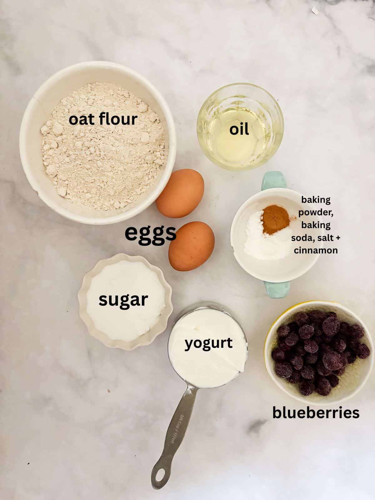 Two-bite, gluten-free mini blueberry muffins are made with whole-grain oat flour, Greek yogurt, and plenty of juicy berries. Kids love them! Ingredients for gluten free mini blueberry muffins are text-labeled.