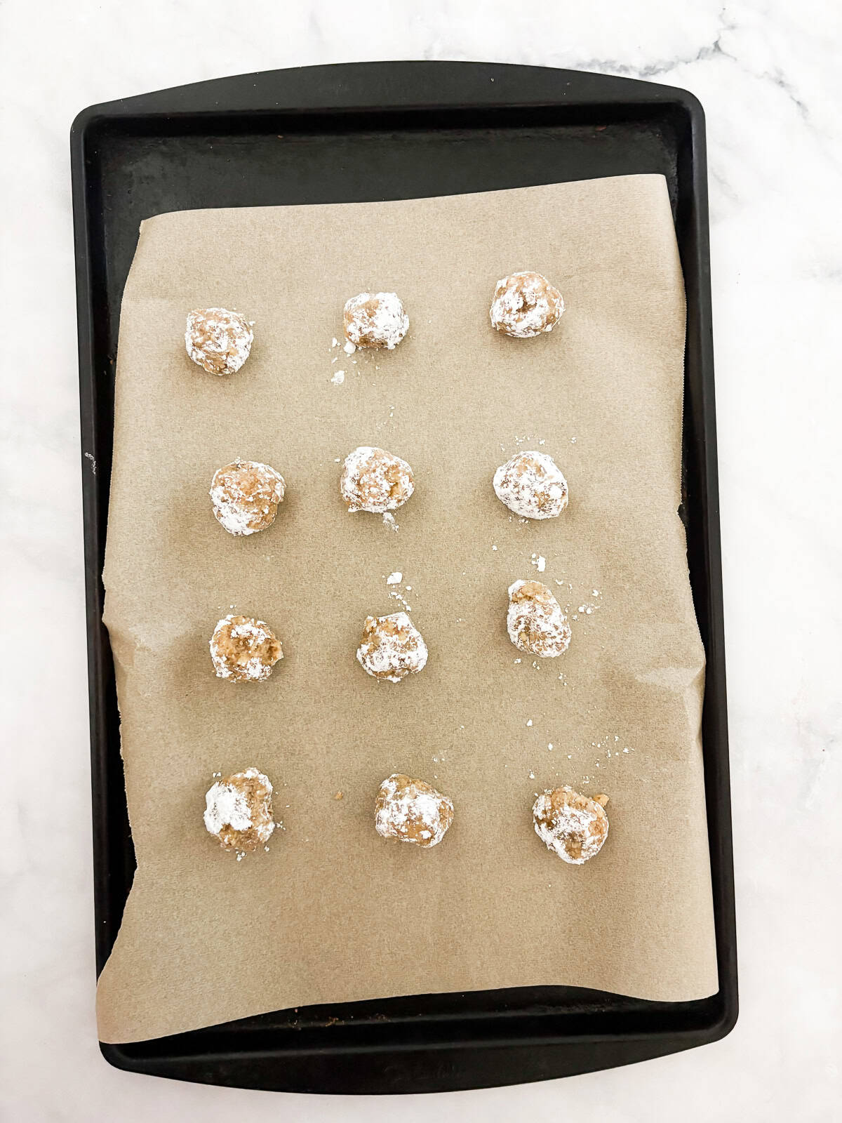 Chewy Moroccan ghriba cookies with walnuts and cinnamon are lightly sweet, rolled in powdered sugar, and easily gluten-free. Ghriba cookies rolled in powdered sugar on a baking sheet.