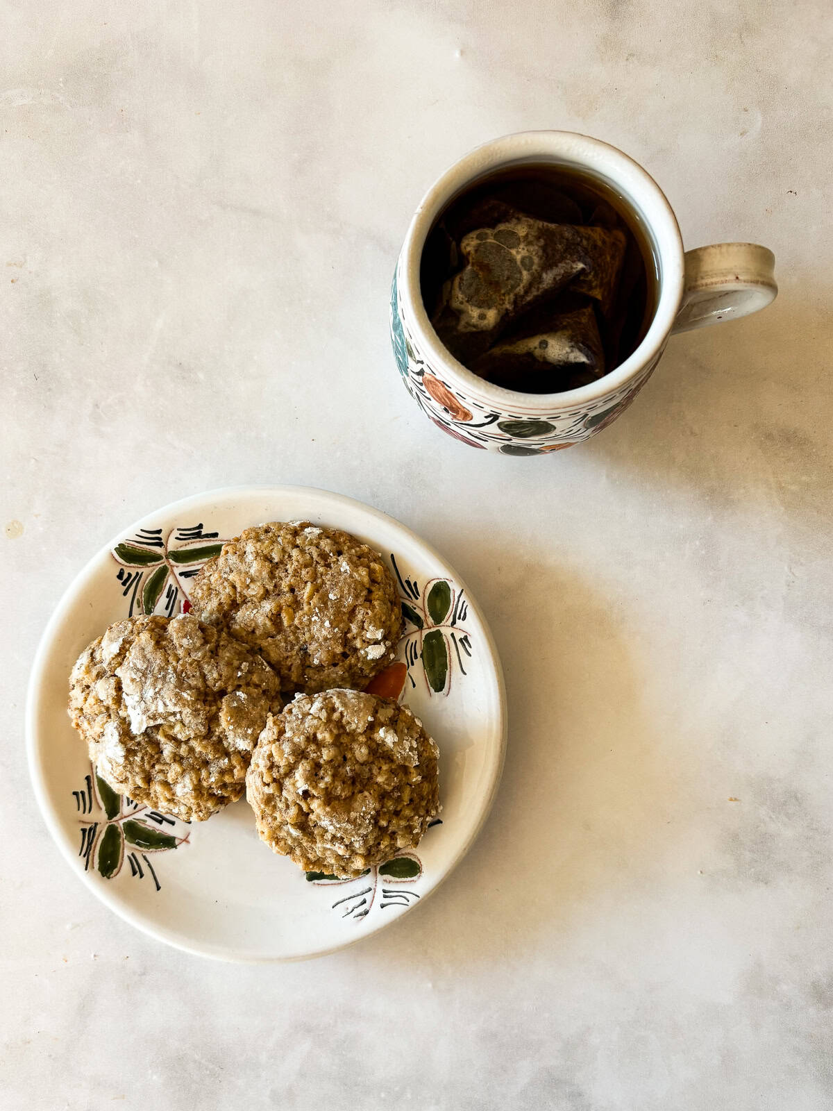 Chewy Moroccan ghriba cookies with walnuts and cinnamon are lightly sweet, rolled in powdered sugar, and easily gluten-free. A small Moroccan plate with ghriba cookies next to a cup of tea.