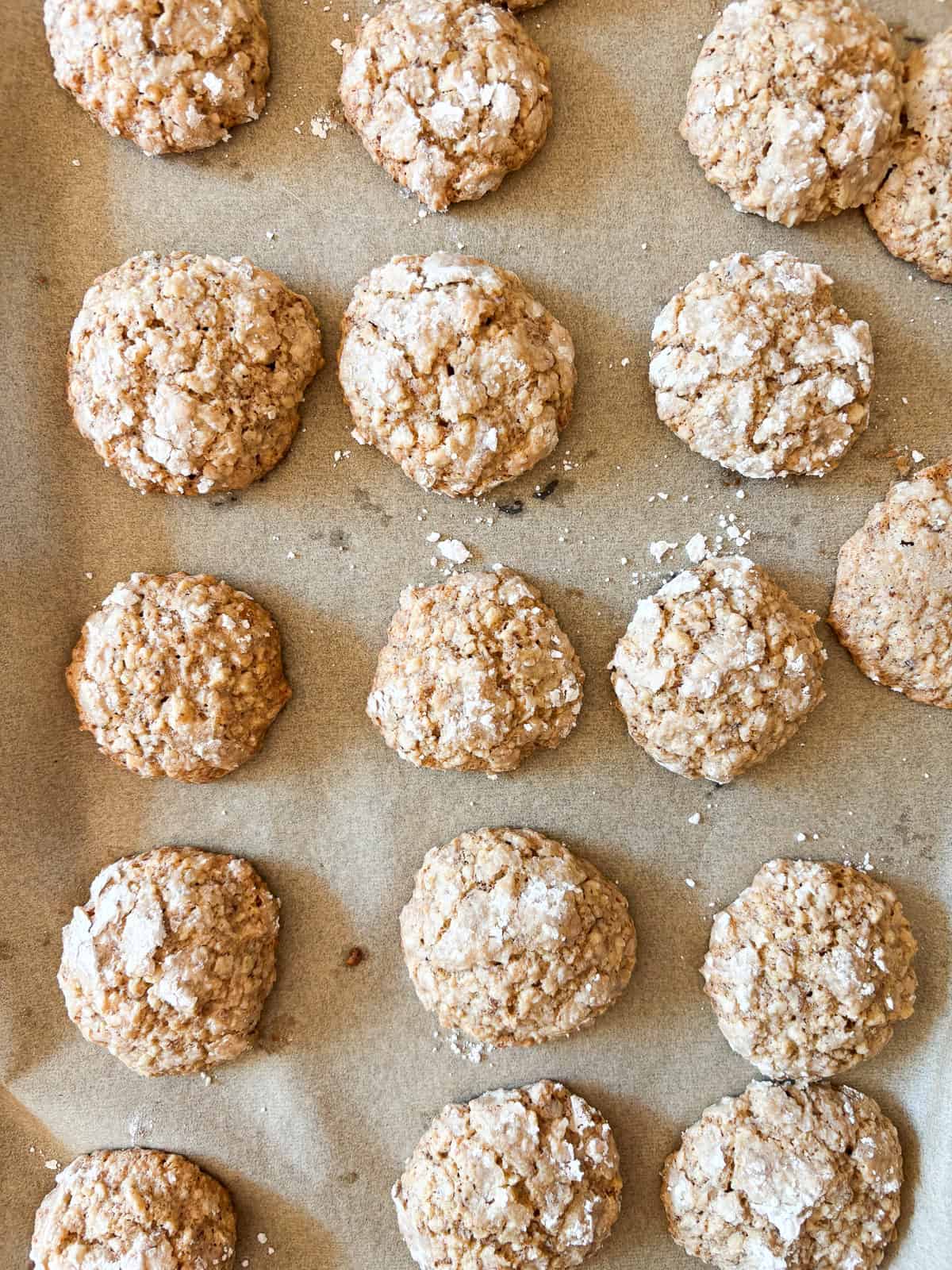 Chewy Moroccan ghriba cookies with walnuts and cinnamon are lightly sweet, rolled in powdered sugar, and easily gluten-free. Ghriba cookies cool on a baking sheet.