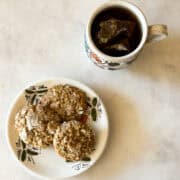 A small Moroccan plate with ghriba cookies next to a cup of tea.