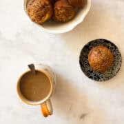 A bowl of gluten free apple banana bread muffins and a cup of coffee.