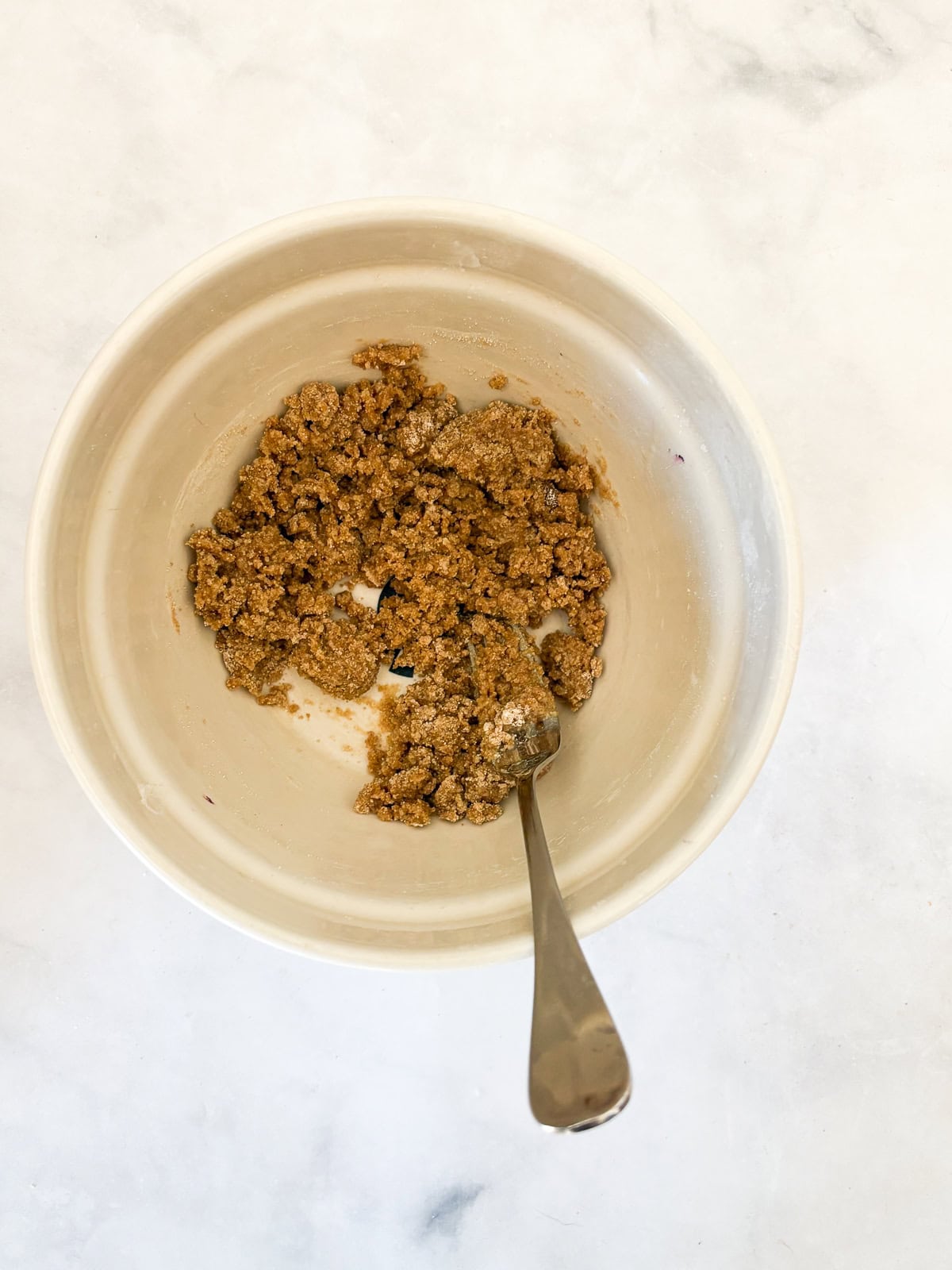 These cakey gluten-free bakery-style blueberry muffins are bursting with berries and topped with a cinnamon-spiked brown sugar crumble. The crumble topping is mixed in a bowl for gluten-free bakery-style blueberry muffins.