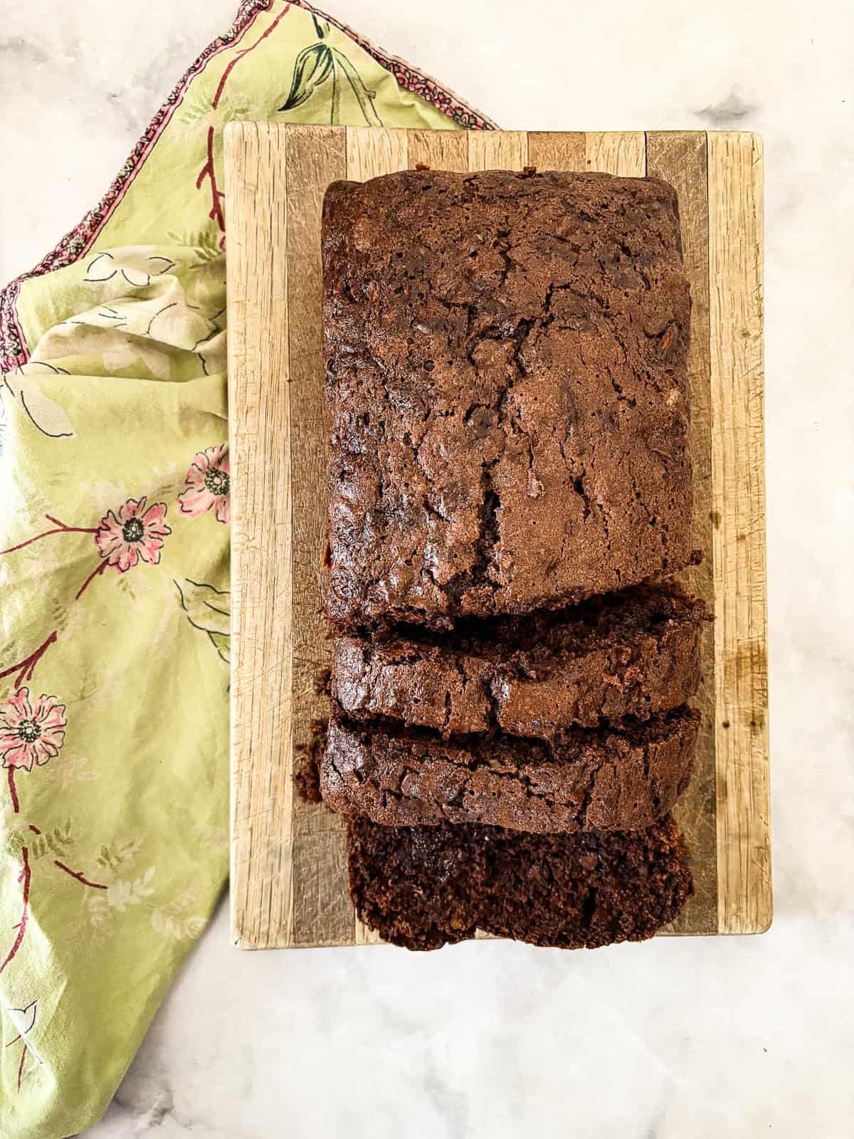 Moist and gloriously chocolatey gluten free chocolate zucchini bread is made with olive oil, plenty of chocolate, and, of course, zucchini! A sliced loaf of gluten free chocolate zucchini bread on a cutting board.