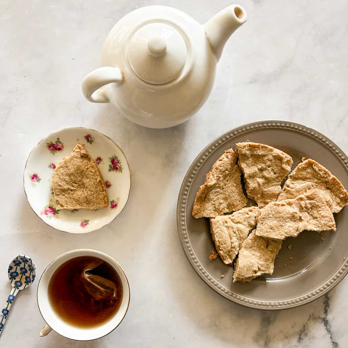A plate of gluten free lavender shortbread cookies, tea, and a tea pot.