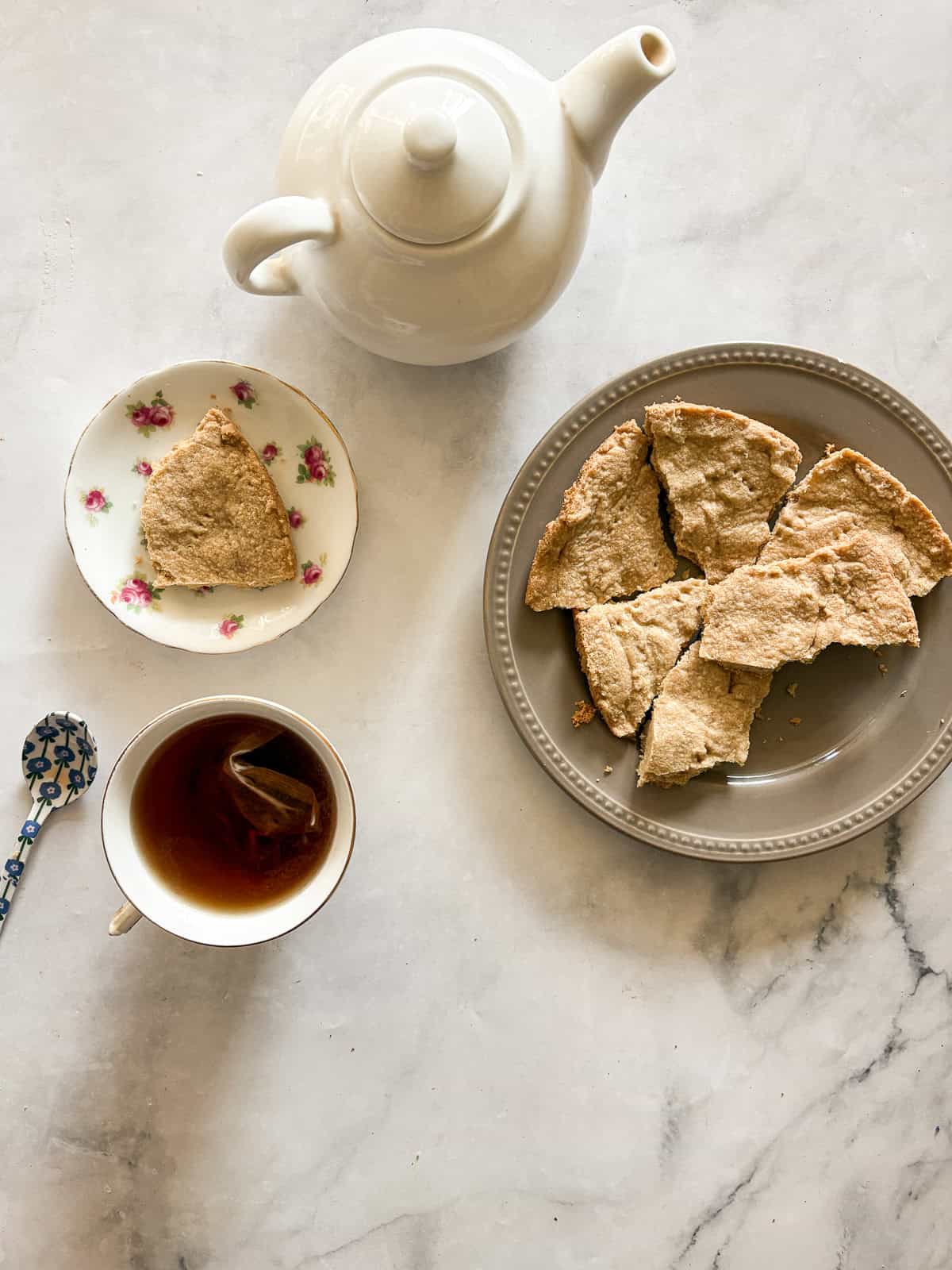 Melt-in-your-mouth gluten free lavender shortbread cookies are made with plenty of butter and infused with a bit of fresh or dried lavender. A plate of gluten free lavender shortbread cookies, tea, and a tea pot.