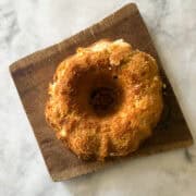 A gluten free lemon bundt cake on a wooden cutting board.