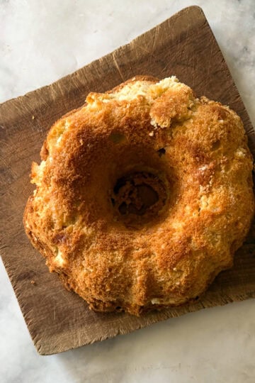 A gluten free lemon bundt cake on a wooden cutting board.