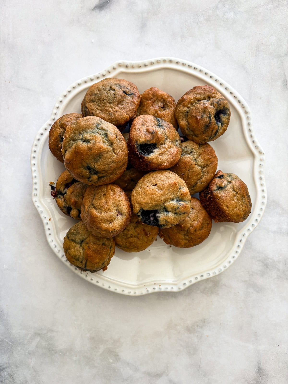 A plate full of gluten free mini blueberry muffins.