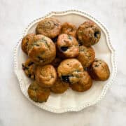 A plate full of gluten free mini blueberry muffins.