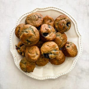 A plate full of gluten free mini blueberry muffins.