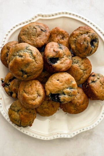 A plate full of gluten free mini blueberry muffins.