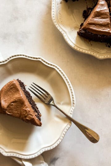 A slice of vegan gluten free chocolate cake on a plate with the cake next to it.