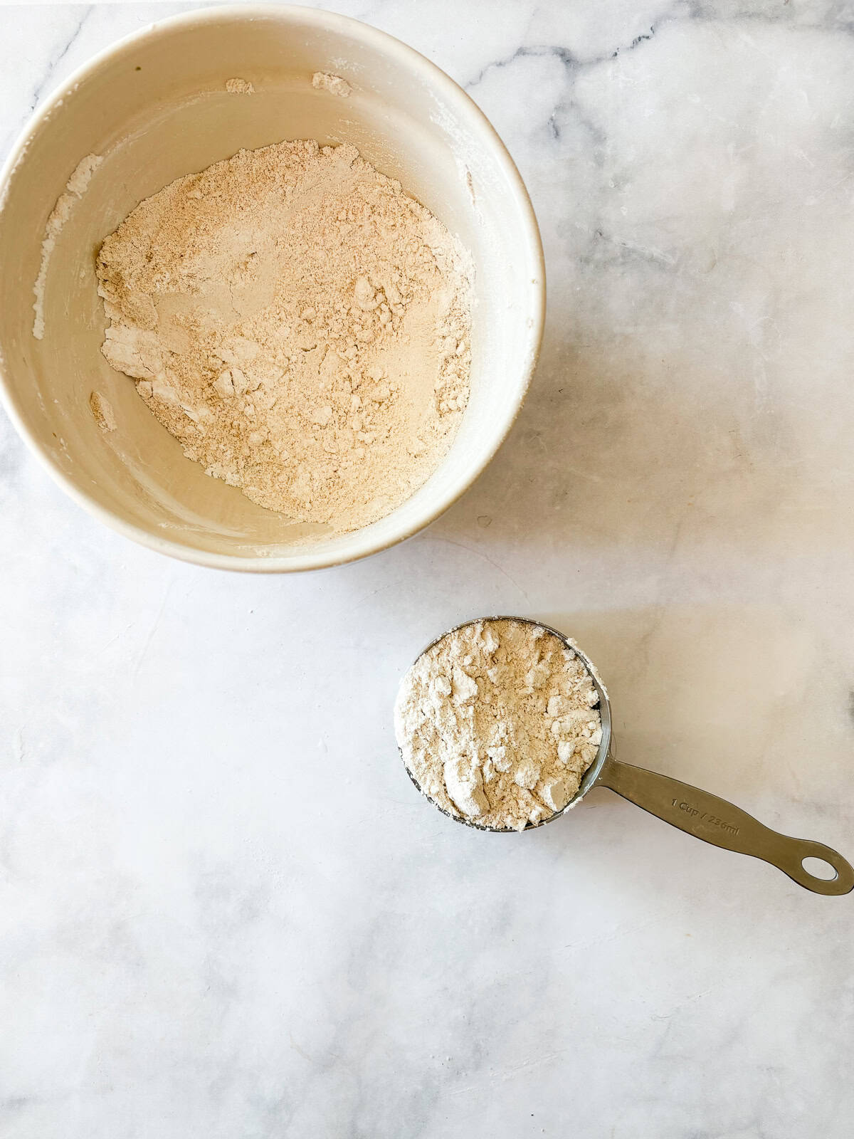 This easy homemade gluten free cake flour is perfect in cakes and more. Gluten-free flour and cornstarch feature in this DIY blend. Homemade gluten free cake flour in a bowl and in a measuring cup.
