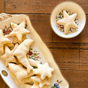A lower sugar sugar cookies star shaped cookie on a plate next to a platter of cookies.