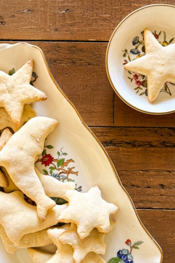 A lower sugar sugar cookies star shaped cookie on a plate next to a platter of cookies.