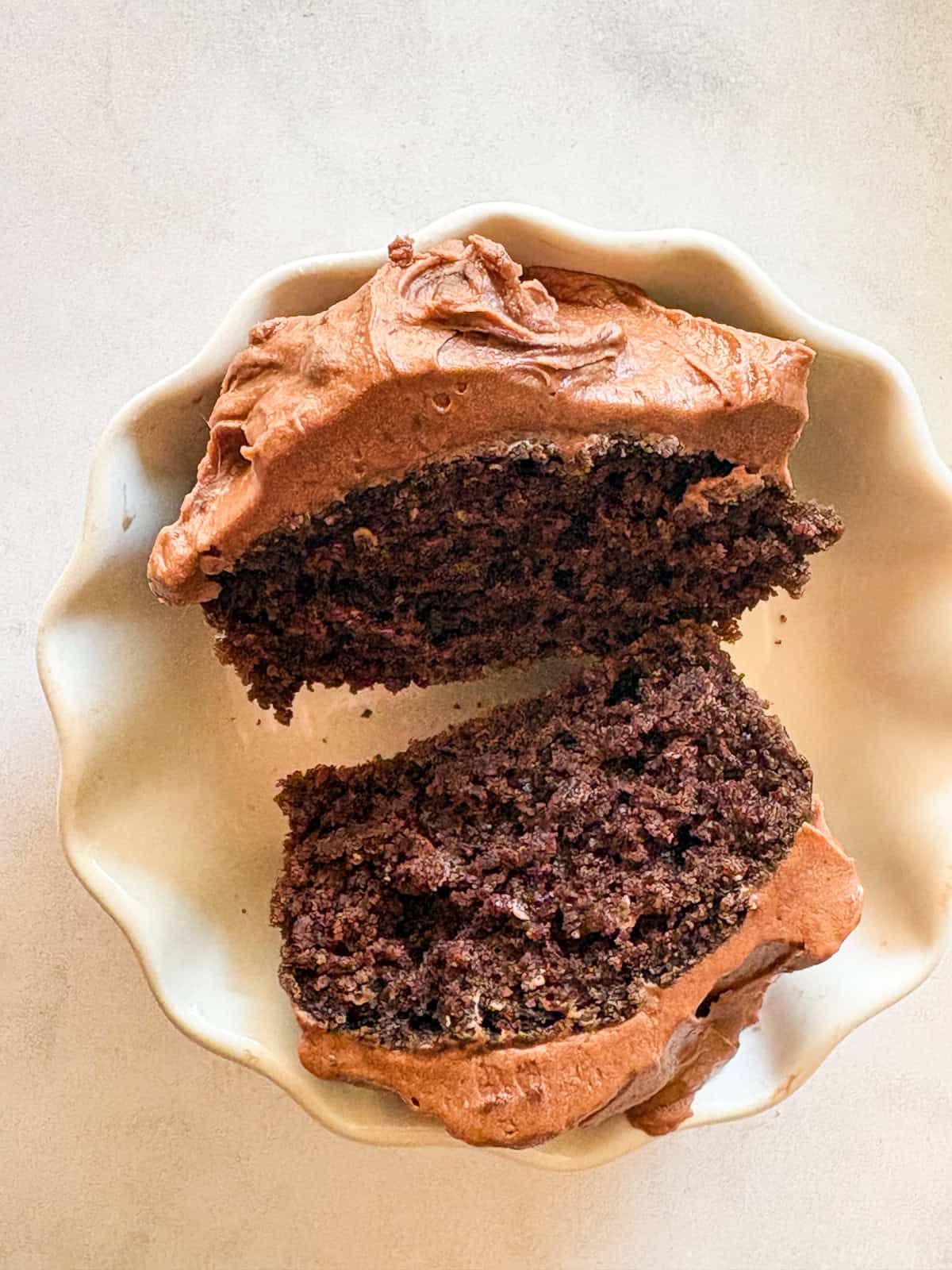Delicious one-bowl vegan gluten-free chocolate cupcakes are made with oat flour and a handful of simple ingredients. So soft and fluffy! A vegan gluten-free chocolate cupcakes is sliced in half to show its interior.