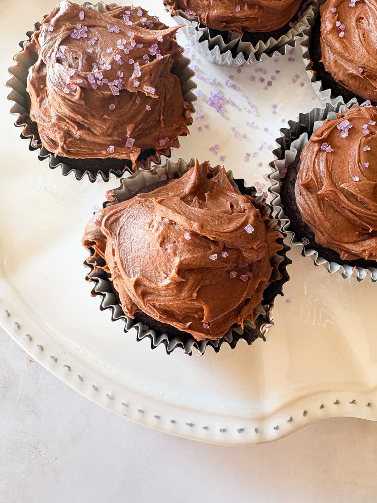 Delicious one-bowl vegan gluten-free chocolate cupcakes are made with oat flour and a handful of simple ingredients. So soft and fluffy! A few vegan gluten-free chocolate cupcakes on a plate.